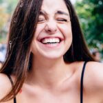 femme en haut noir à bretelles spaghetti souriante